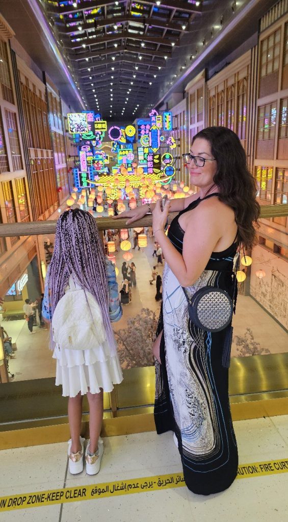Adult and child looking down over a colourful indoor market space in Dubai