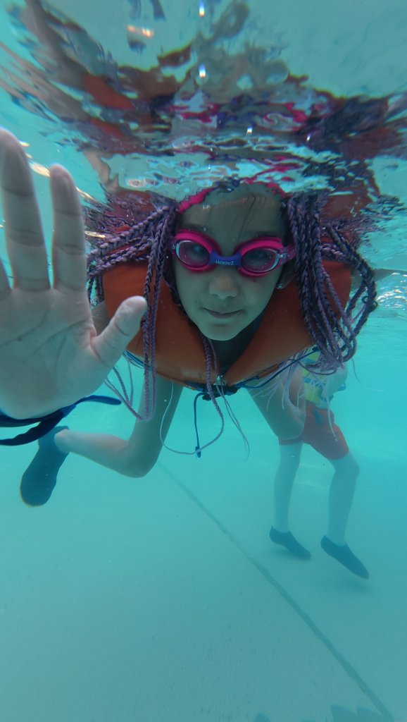 Person swimming underwater in a clear pool wearing goggles in Dubai