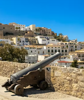 Historic cannon overlooking white buildings and hillside in Ibiza old town