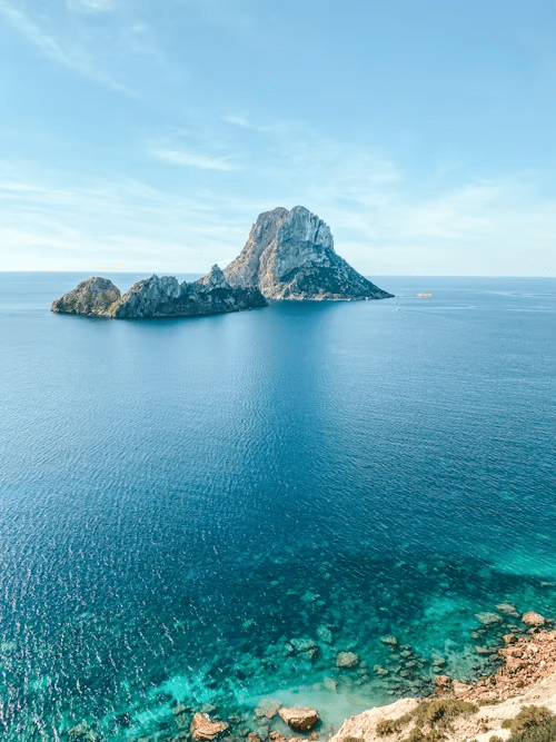 Rocky island rising from clear blue sea off the coast of Ibiza
