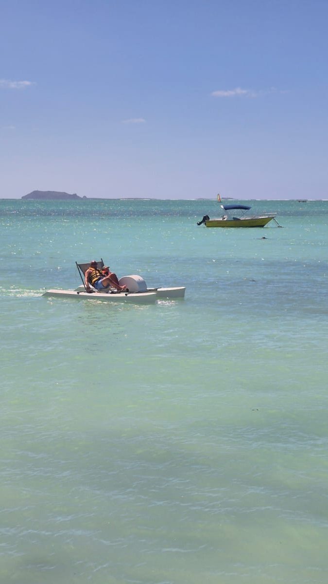 People relaxing on a small pedal boat on clear shallow sea in Mauritius